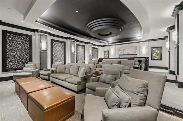 home theater room with ornate columns, a raised ceiling, and ornamental molding