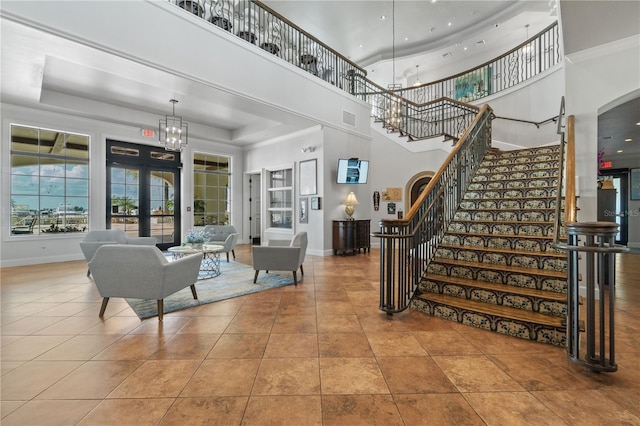 living room with french doors, light tile patterned floors, a tray ceiling, and a high ceiling