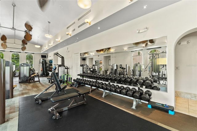 gym with high vaulted ceiling and ceiling fan