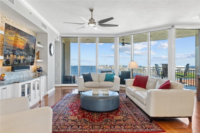 living room featuring a water view, ceiling fan, dark wood-type flooring, and floor to ceiling windows