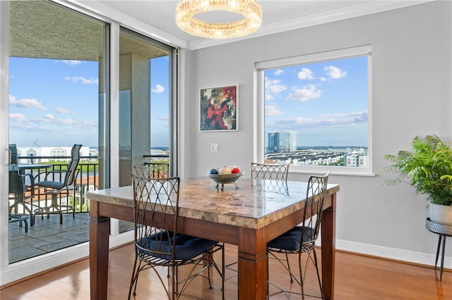 dining room featuring crown molding, wood-type flooring, and an inviting chandelier