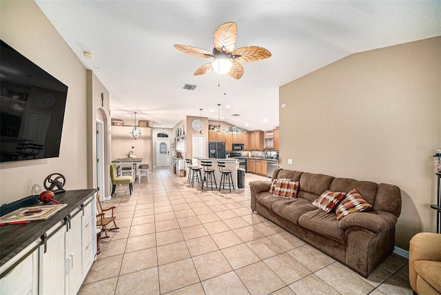 tiled living room featuring lofted ceiling, ceiling fan, and a textured ceiling