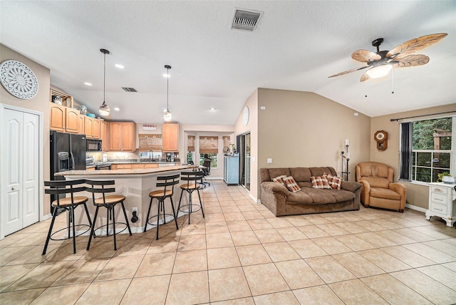 kitchen with a breakfast bar, lofted ceiling, black appliances, and a healthy amount of sunlight