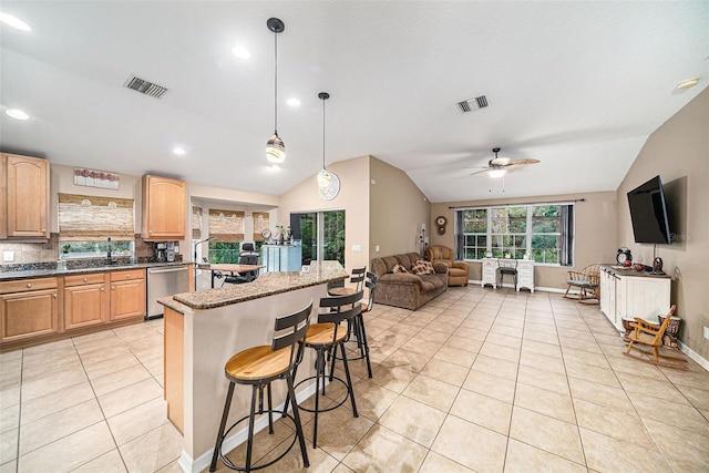 kitchen with ceiling fan, decorative light fixtures, a kitchen bar, vaulted ceiling, and decorative backsplash