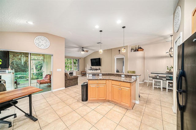 kitchen featuring light stone counters, ceiling fan, light tile patterned flooring, vaulted ceiling, and black refrigerator