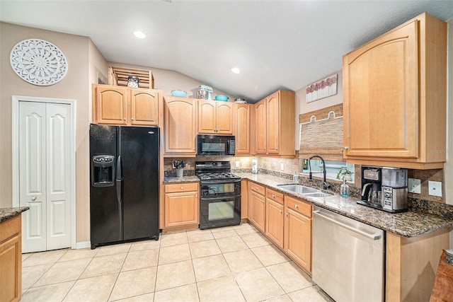 kitchen featuring dark stone countertops, lofted ceiling, sink, and black appliances