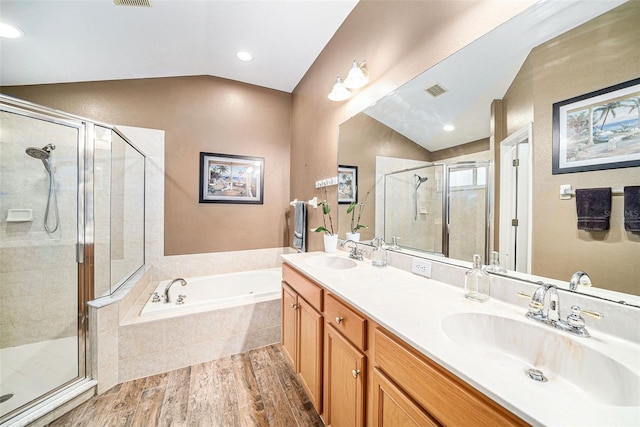 bathroom with plus walk in shower, vaulted ceiling, hardwood / wood-style flooring, and vanity