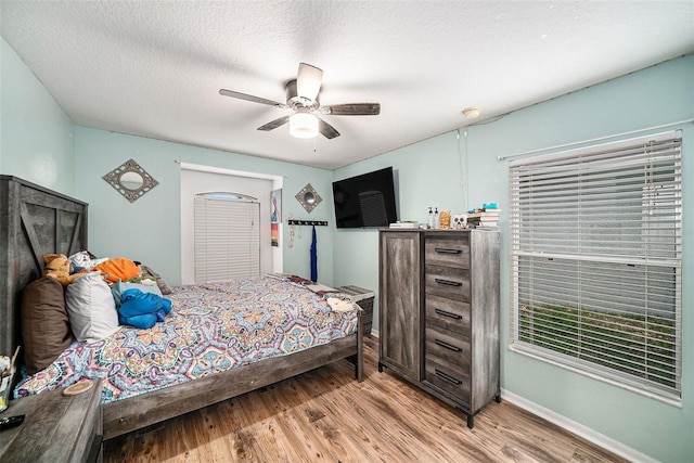 bedroom featuring light hardwood / wood-style flooring, ceiling fan, and a textured ceiling