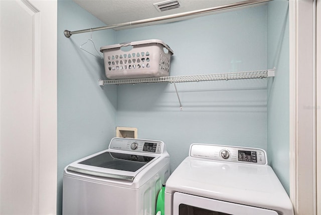 laundry room featuring a textured ceiling and washer and dryer