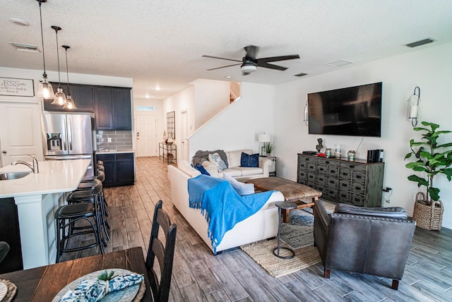 living room with a textured ceiling, ceiling fan, and sink