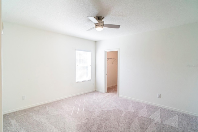 spare room featuring light carpet, ceiling fan, and a textured ceiling