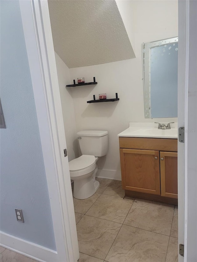 bathroom with tile patterned flooring, a textured ceiling, vanity, and toilet