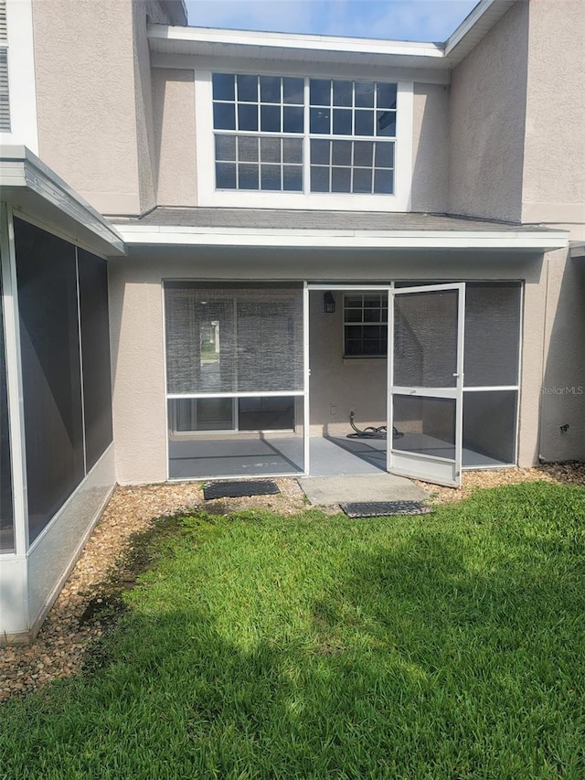 rear view of property with a sunroom, a patio, and a lawn