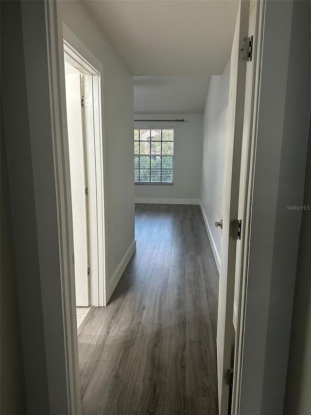 hallway with a textured ceiling and dark wood-type flooring