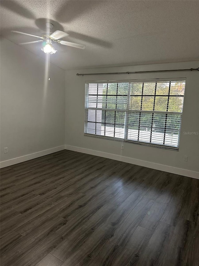 spare room with a textured ceiling, dark hardwood / wood-style floors, ceiling fan, and plenty of natural light