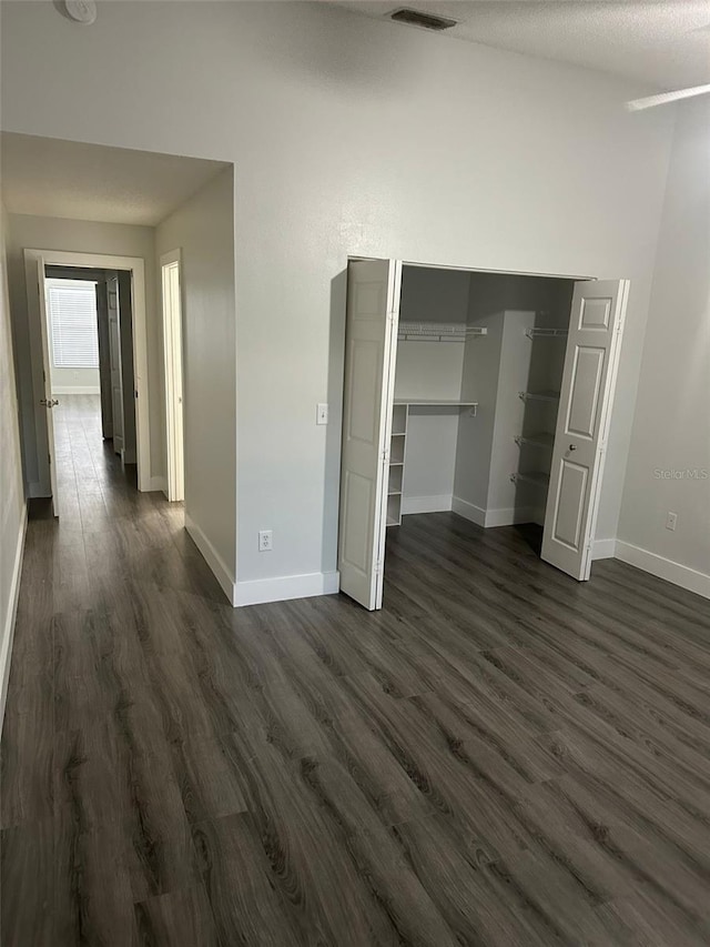 unfurnished bedroom featuring dark hardwood / wood-style floors and a closet