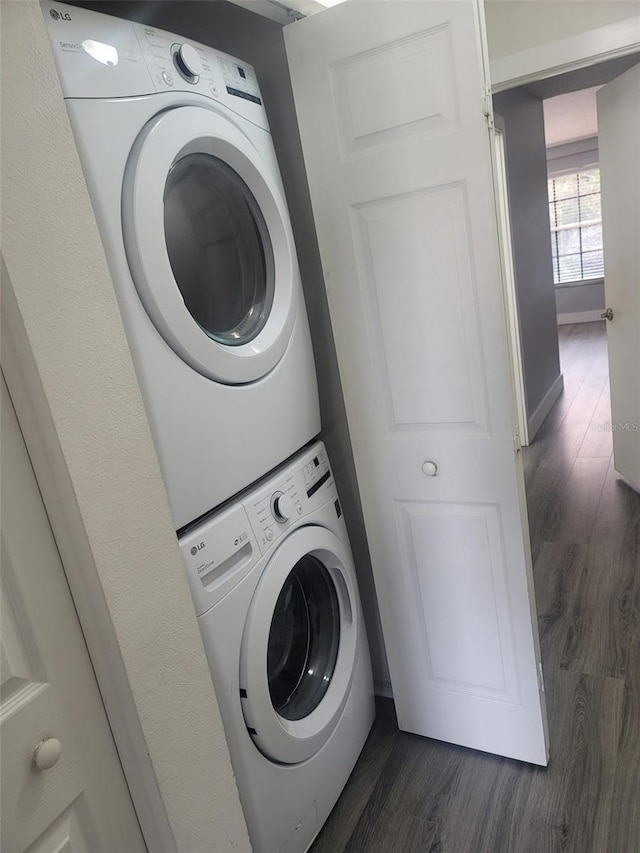 clothes washing area with stacked washer / dryer and dark hardwood / wood-style flooring