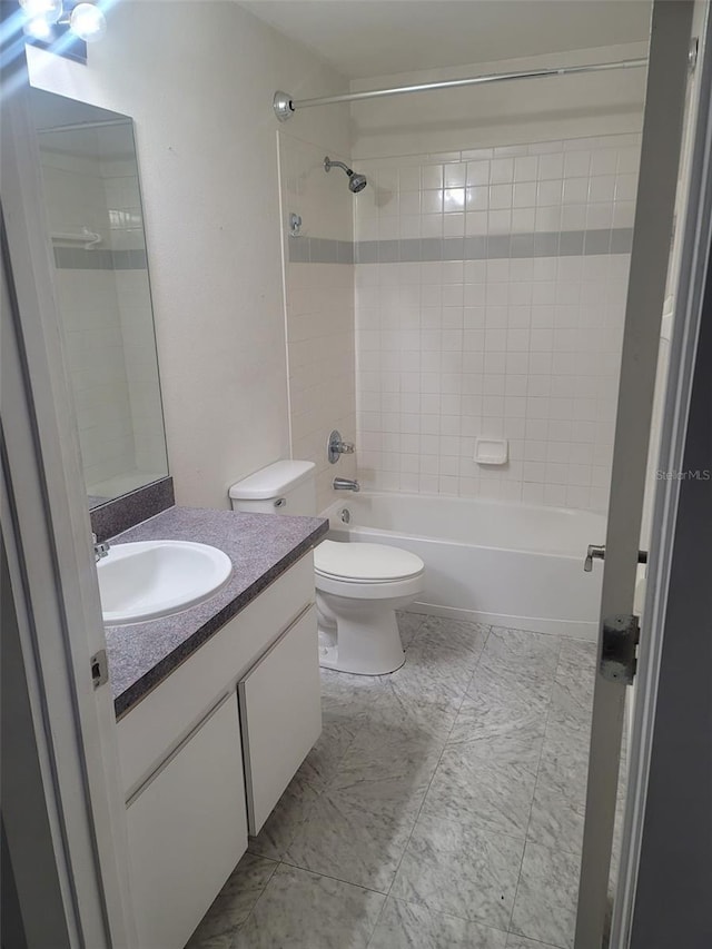 full bathroom featuring tiled shower / bath, vanity, and toilet