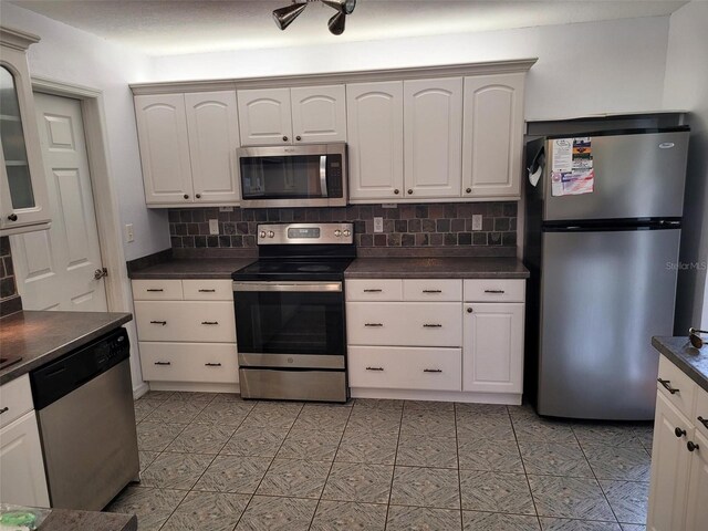 10908 Claymont Dr, New Port Richey, FL 34654 - kitchen featuring appliances with stainless steel finishes, dark countertops, tasteful backsplash, and white cabinetry