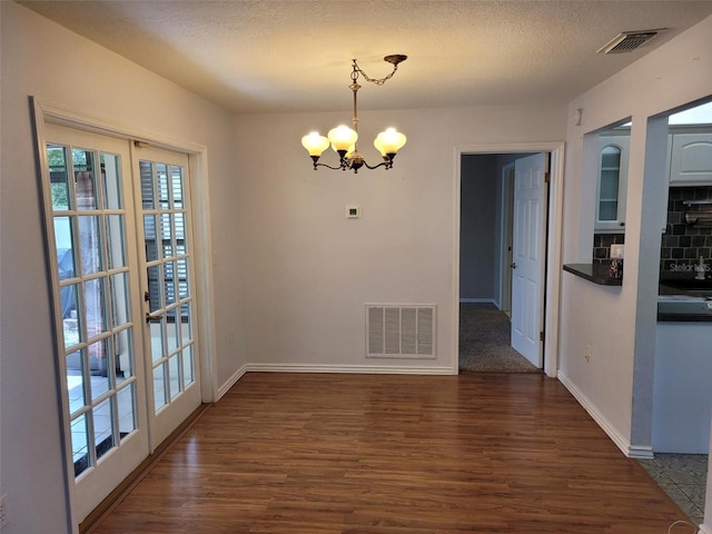 10908 Claymont Dr, New Port Richey, FL 34654 - unfurnished dining area with a chandelier, dark wood finished floors, baseboards, and a textured ceiling