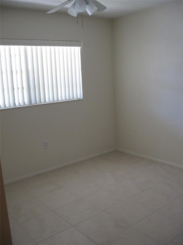 tiled empty room with ceiling fan and a textured ceiling