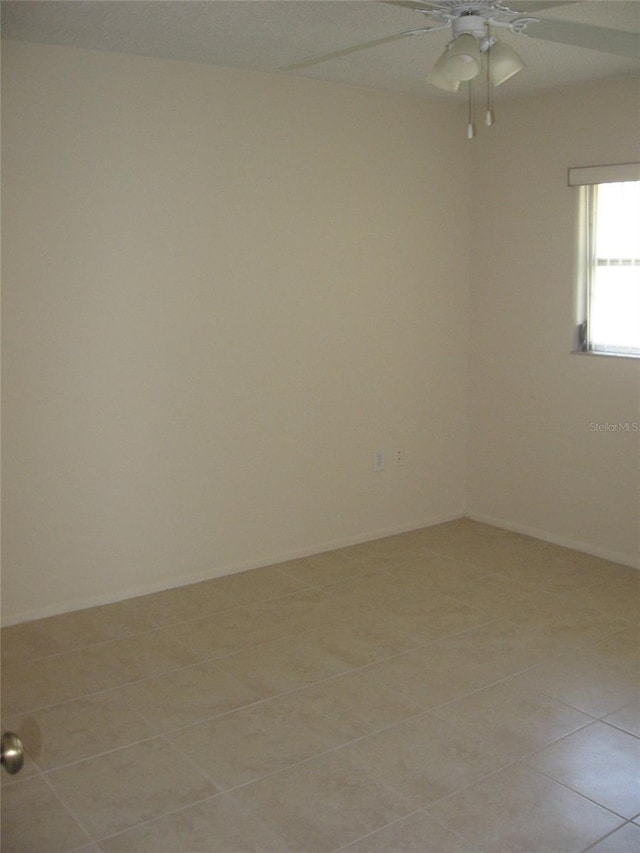 empty room with a ceiling fan and light tile patterned flooring