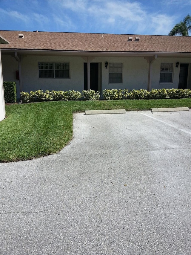 view of front of property featuring stucco siding, uncovered parking, and a front lawn