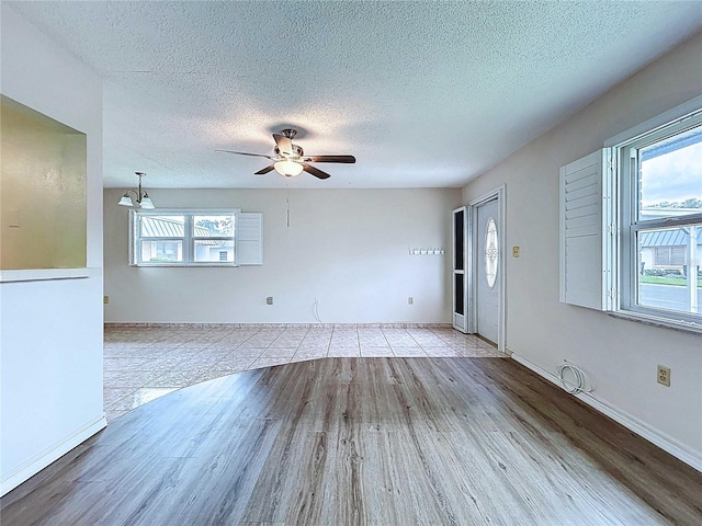 11920 Boynton Ln Unit 11920, New Port Richey, FL 34654 - unfurnished living room featuring baseboards, a ceiling fan, wood finished floors, and a textured ceiling