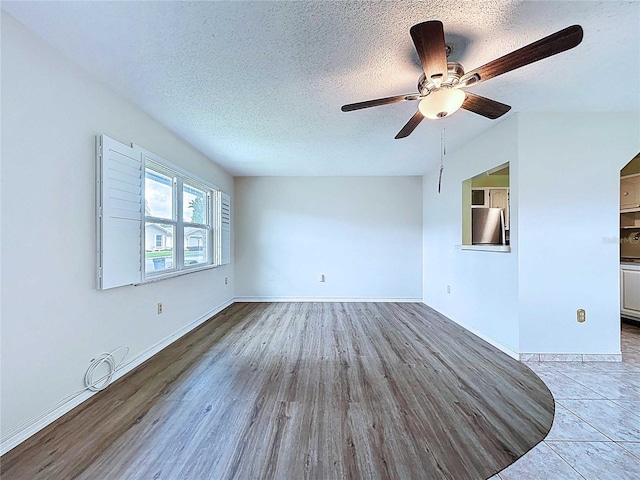 11920 Boynton Ln Unit 11920, New Port Richey, FL 34654 - unfurnished living room featuring a ceiling fan, baseboards, a textured ceiling, and light wood-style floors