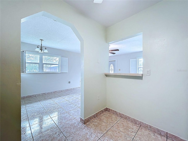 11920 Boynton Ln Unit 11920, New Port Richey, FL 34654 - unfurnished room with ceiling fan with notable chandelier, light tile patterned flooring, arched walkways, and a healthy amount of sunlight