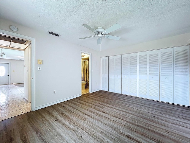 11920 Boynton Ln Unit 11920, New Port Richey, FL 34654 - unfurnished bedroom featuring a textured ceiling, visible vents, baseboards, wood finished floors, and ensuite bath