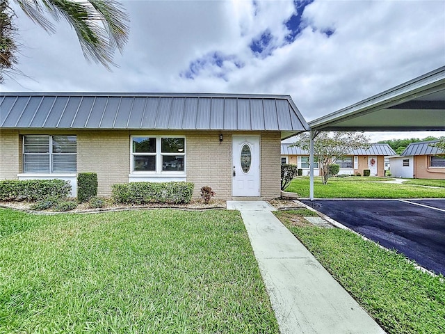 11920 Boynton Ln Unit 11920, New Port Richey, FL 34654 - view of front of home featuring brick siding, a carport, a front lawn, and metal roof