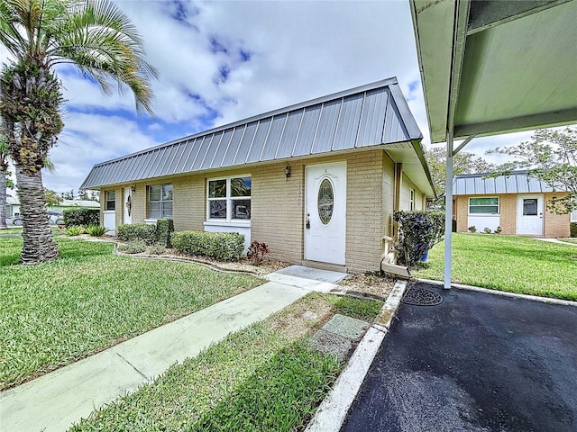 11920 Boynton Ln Unit 11920, New Port Richey, FL 34654 - view of front of home with brick siding, a front yard, and metal roof