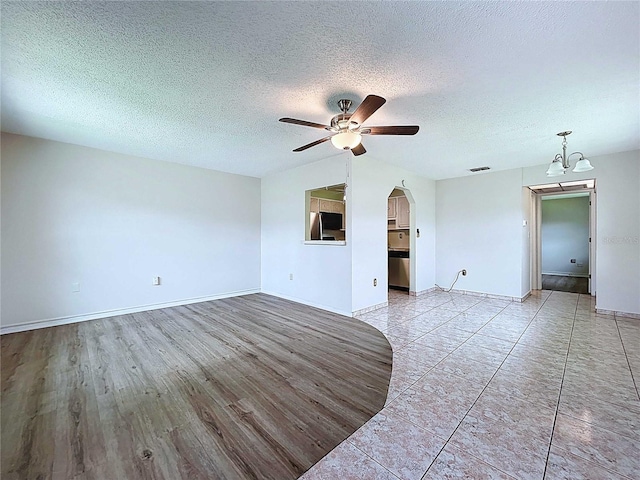 11920 Boynton Ln Unit 11920, New Port Richey, FL 34654 - unfurnished living room featuring ceiling fan with notable chandelier, baseboards, visible vents, and arched walkways