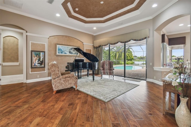 sitting room with a tray ceiling, crown molding, and dark wood-type flooring