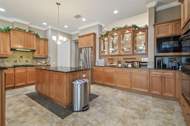 kitchen with dark stone counters, crown molding, stainless steel appliances, hanging light fixtures, and a center island