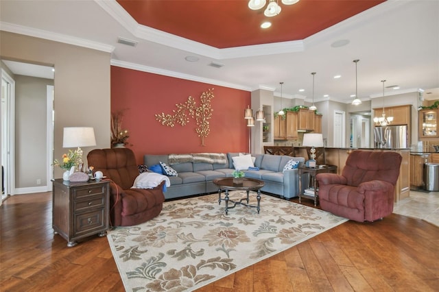 living room featuring a tray ceiling, dark hardwood / wood-style floors, ornamental molding, and a chandelier