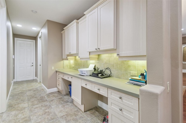 kitchen with white cabinets, built in desk, light tile patterned floors, and tasteful backsplash