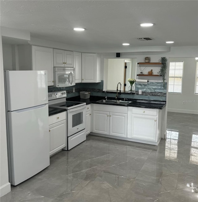 kitchen with decorative backsplash, sink, white cabinets, and white appliances