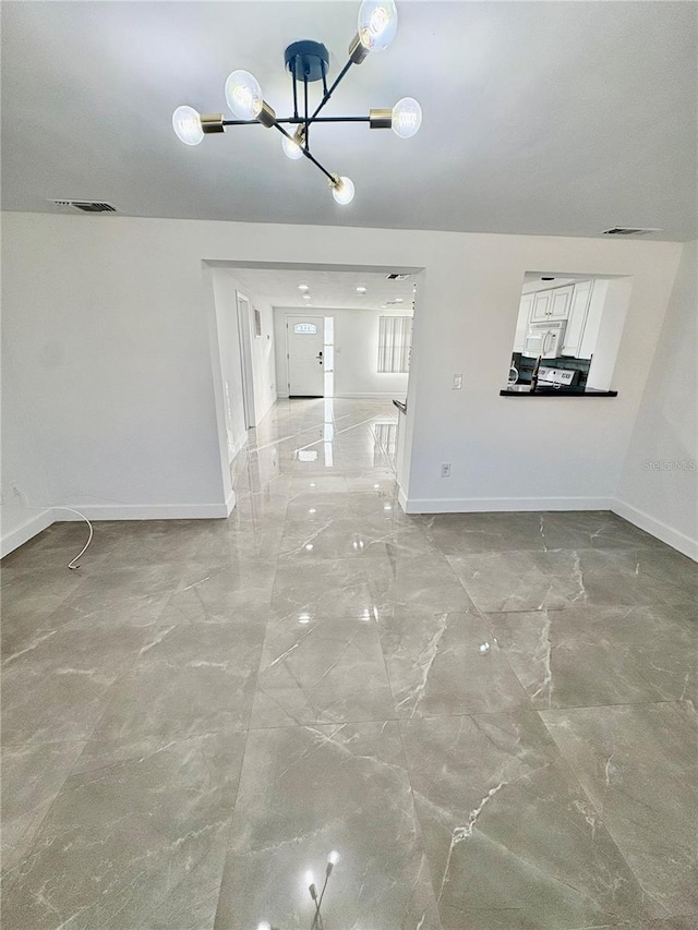 unfurnished living room featuring a chandelier