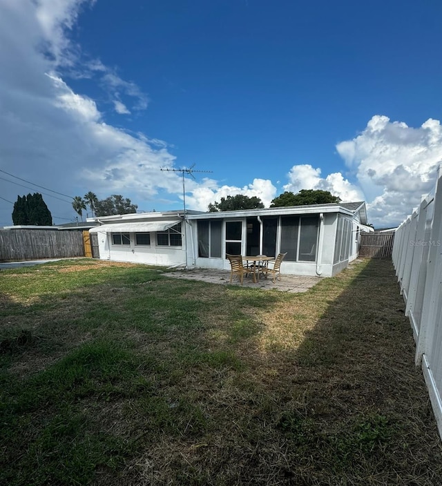 back of property with a lawn and a sunroom