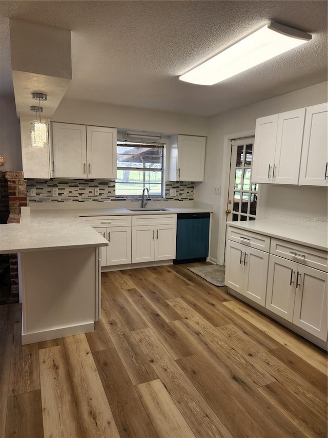 kitchen with dishwasher, light wood-type flooring, sink, and pendant lighting