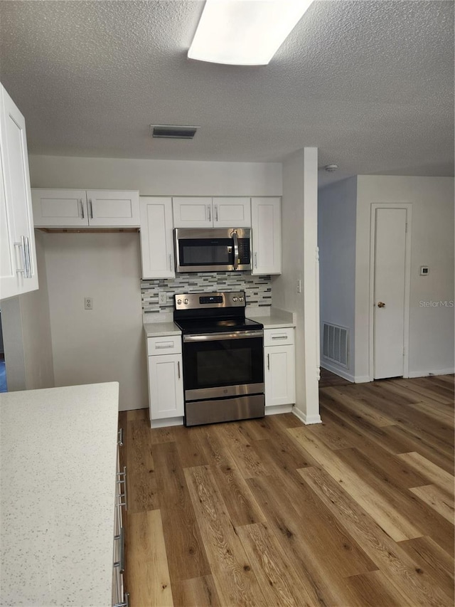 kitchen with white cabinets, hardwood / wood-style floors, and stainless steel appliances