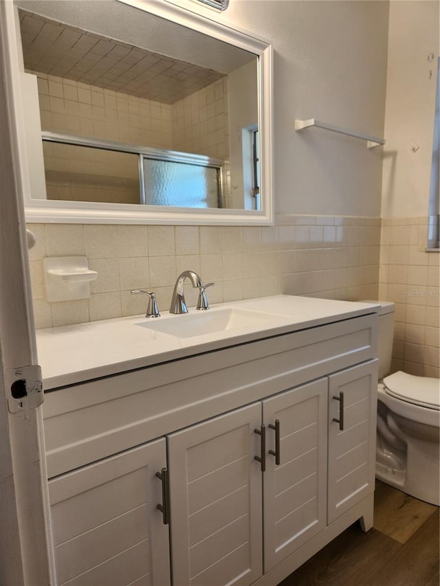 bathroom with tile walls, hardwood / wood-style floors, vanity, and toilet