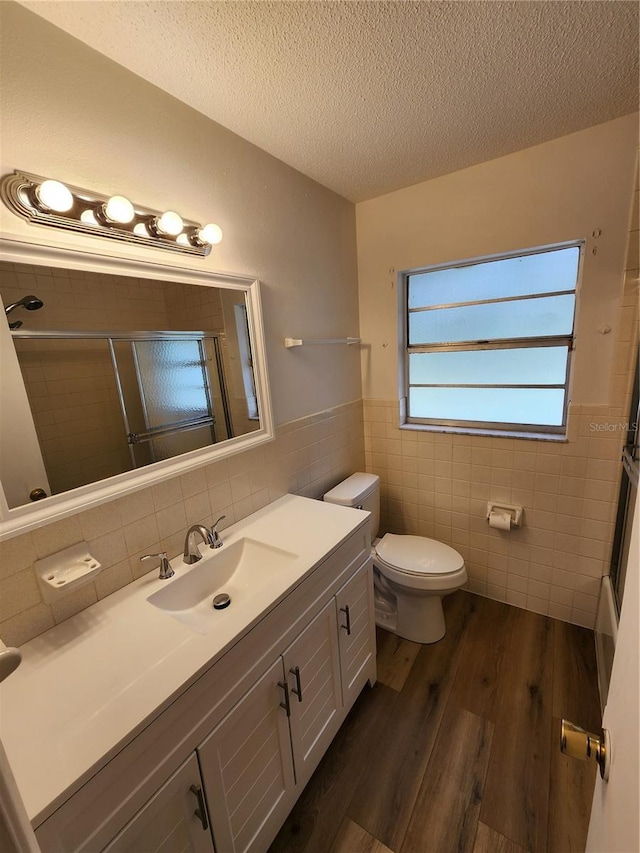 bathroom featuring toilet, tile walls, wood-type flooring, and a textured ceiling