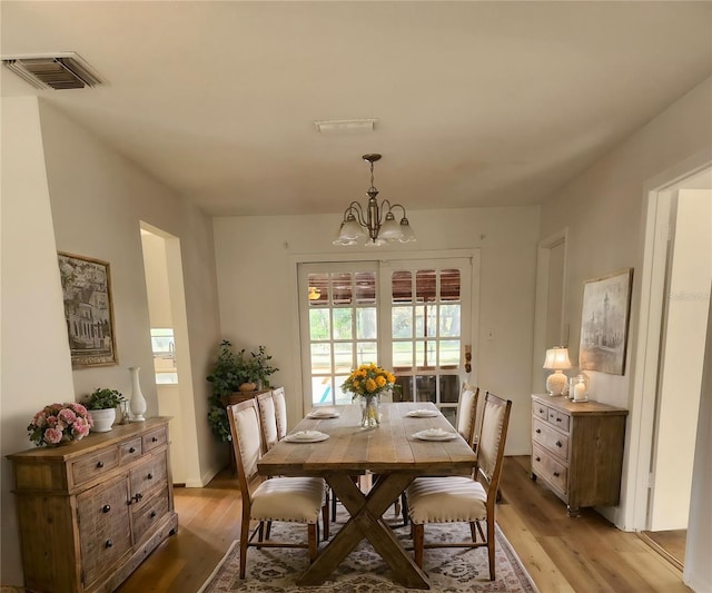 dining space featuring light hardwood / wood-style floors and a chandelier