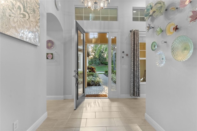 tiled entryway with a notable chandelier and a towering ceiling