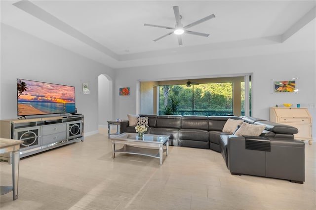 living room with a tray ceiling and ceiling fan