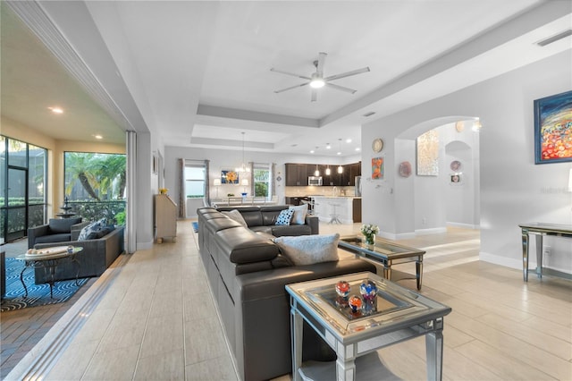 living room featuring a tray ceiling and ceiling fan