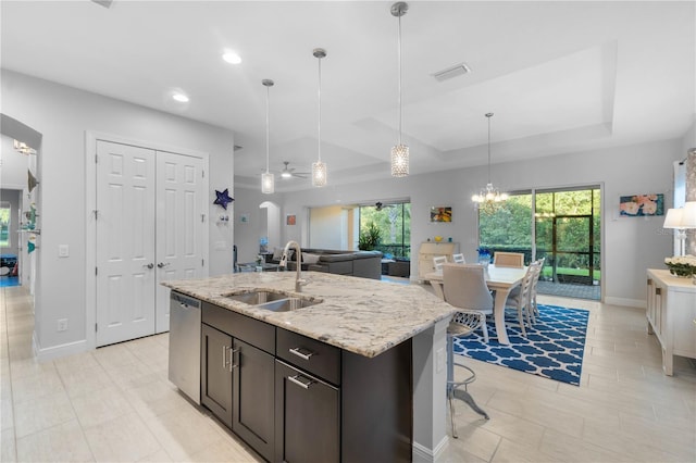 kitchen featuring a raised ceiling, sink, hanging light fixtures, stainless steel dishwasher, and dark brown cabinetry